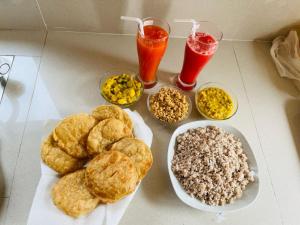 einen Tisch mit einem Teller Essen und zwei Getränken in der Unterkunft Janas Blue Water Corner in Trincomalee