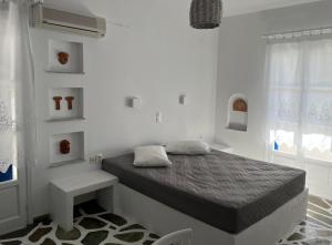 a white bedroom with a bed and a window at Angie's Studios in Parikia