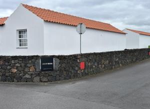 uma parede de pedra em frente a um edifício branco em Casas do Verdelho em Madalena