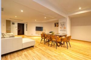 un soggiorno con divano bianco, tavolo e sedie di Luxurious 3 Bedroom Apartment in Herastrau a Bucarest