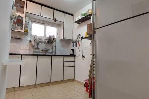  La cuisine est équipée de placards blancs et d'un réfrigérateur. dans l'établissement הנביאים 1 נתניה Naveim apartment, à Netanya
