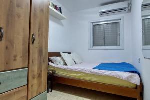 a small bedroom with a bed and a window at הנביאים 1 נתניה Naveim apartment in Netanya