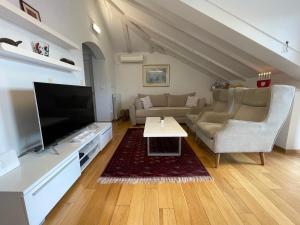 uma sala de estar com um sofá, uma televisão e uma mesa em Holiday Residence Zvono em Mlini
