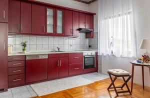 uma cozinha com armários vermelhos e uma mesa com um banco em Holiday Home Sviba em Varaždinske Toplice