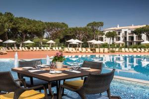 a dining table and chairs next to a swimming pool at Pine Cliffs Residence, a Luxury Collection Resort, Algarve in Albufeira