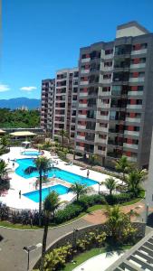 a large pool with palm trees in front of a large building at Apartamento clube próximo à praia in Caraguatatuba