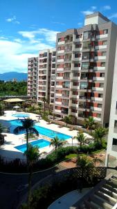 a large apartment building with several pools and palm trees at Apartamento clube próximo à praia in Caraguatatuba