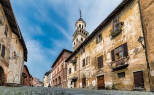 una vecchia strada con una torre dell'orologio sullo sfondo di La Stanza dei Sogni a Saluzzo