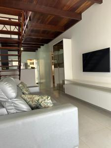 a living room with a white couch and a flat screen tv at Casa Praia dos Carneiros in Tamandaré