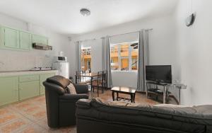 a living room with a couch and a tv and a kitchen at Wanna Studio Apartments in Pointe aux Cannoniers