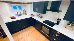 a kitchen with black cabinets and white counter tops at SPINDRIFT is A Beautiful Newly Refurbished THREE BEDROOM Private Family House located on the OLD HARBOUR and the COASTAL PATH in the Heart of Beautiful POLPERRO in Polperro