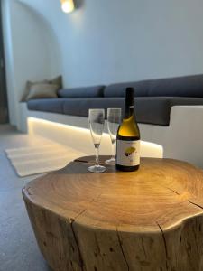 una bottiglia di vino e due bicchieri di vino su un tavolo di legno di Saba Luxury Suites a Karterados