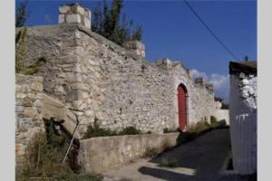 Kastorio-Villy's Guest House في Kastórion: مبنى حجري قديم بباب احمر