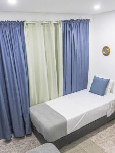 Cama en habitación con cortinas azules en Apartamento Mágico p/ momentos Memoráveis, en Santa Maria