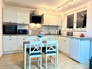 a kitchen with white cabinets and a table and chairs at Black Forest Valley - Nähe Europa Park & Rulantica in Burgheim