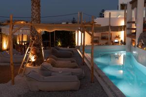 a pool with lounge chairs next to a hotel at Sandaya Luxury Suites in Naousa