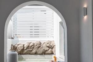 an arched window with a bed in a room at Sandaya Luxury Suites in Naousa