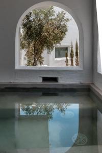 una ventana abierta con reflejo en una piscina de agua en Sandaya Luxury Suites, en Naousa