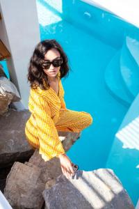 a woman sitting on rocks next to a swimming pool at Sandaya Luxury Suites in Naousa