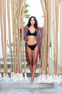 a woman in a bikini is standing between curtains at Sandaya Luxury Suites in Naousa