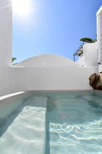 a swimming pool in front of a house at Sandaya Luxury Suites in Naousa