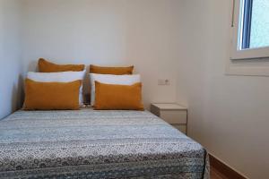 1 cama con almohadas de color naranja y blanco en una habitación en Casa rural en San Vicente de O Grove, en O Grove