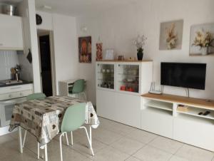 a living room with a table and a tv in a kitchen at Casa SolyMar Canarias 6 in Caleta De Fuste