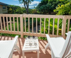 a pair of white chairs and a table on a deck at Poipu Plantation Vacation Rentals in Koloa
