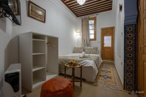 a bedroom with a bed and a table with a stool at Riad Bin Souaki in Chefchaouene