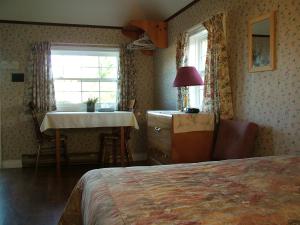 um quarto com uma cama, uma mesa e uma janela em Avonlea Cottages em Cavendish