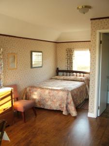 a bedroom with a large bed and a chair at Avonlea Cottages in Cavendish