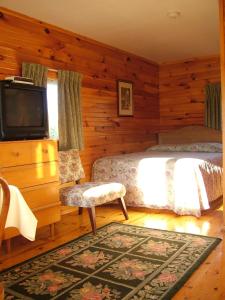 1 dormitorio con 1 cama y TV de pantalla plana en Avonlea Cottages, en Cavendish