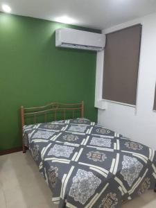 1 dormitorio con cama y pared verde en Remodeled Downtown Apartment - Centro de Guayaquil, en Guayaquil