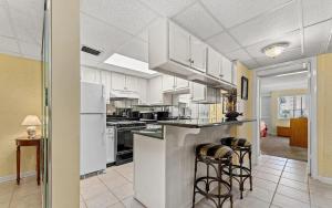 a kitchen with white cabinets and bar stools at Sugar Beach Condo in Panama City Beach