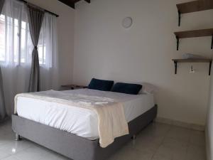 Schlafzimmer mit einem Bett mit weißer Bettwäsche und einem Fenster in der Unterkunft Road Living Home in Medellín