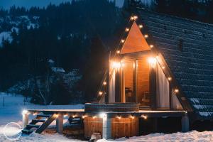una cabaña de madera con luces en la nieve en SouL EsCaPe, en Bălan