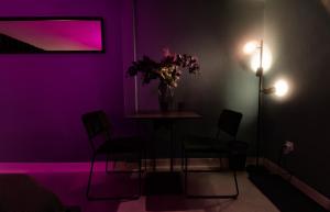 Reeperbahn Unique Boutique Apartments في هامبورغ: غرفة أرجوانية مع طاولة مع كراسي و إناء من الزهور