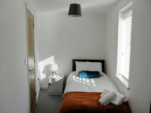 a white bedroom with a bed and a window at Apartment Balmoral Road in Northampton