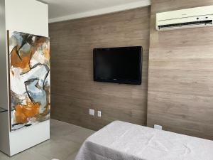 1 dormitorio con TV de pantalla plana en la pared en Flat Studio Boa Viagem, en Recife