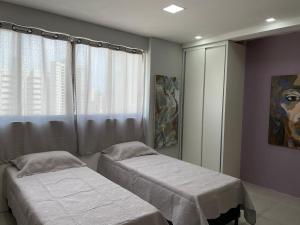 1 dormitorio con 2 camas y una ventana con una pintura en Flat Studio Boa Viagem, en Recife