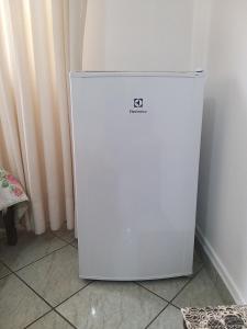 a white refrigerator sitting on the floor in a room at Flat 206 Hotel Cavalinho Branco (3 piscinas, elevador, sauna) in Águas de Lindóia