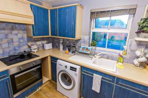 a kitchen with blue cabinets and a washing machine at Lovely apartment easy access to London in West Thurrock