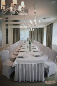 uma mesa longa num quarto com cadeiras brancas em Hotel Millenium em Żyraków