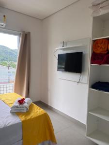 Dieses weiße Zimmer verfügt über ein Bett und einen TV. in der Unterkunft Pousada Suites Enseada Guaruja in Guarujá