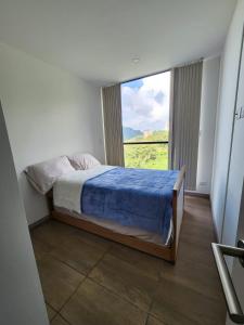 - une chambre avec un lit et une grande fenêtre dans l'établissement Apartamento Amoblado en Manizales, à Manizales