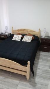 Un dormitorio con una gran cama de madera con sábanas negras. en Leosanmareta en 