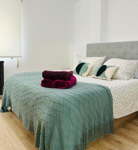 a bed with a green blanket and pillows on it at Industrial -Apartamentos Birdie- in Albacete
