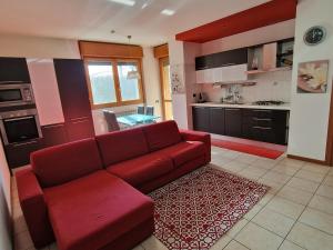 sala de estar con sofá rojo y cocina en Appartamento Volta, en Rho