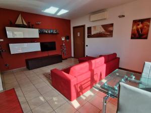 sala de estar con muebles de color rojo y TV de pantalla plana en Appartamento Volta, en Rho