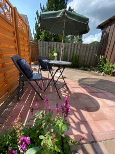eine Terrasse mit einem Tisch, einem Sonnenschirm und Stühlen in der Unterkunft Idyllisches Wohnen in Bad Bramstedt in Bad Bramstedt